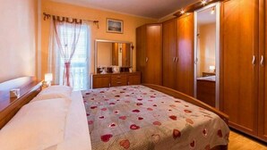 Una camera da letto con un letto, un armadio, una cassettiera e uno specchio.