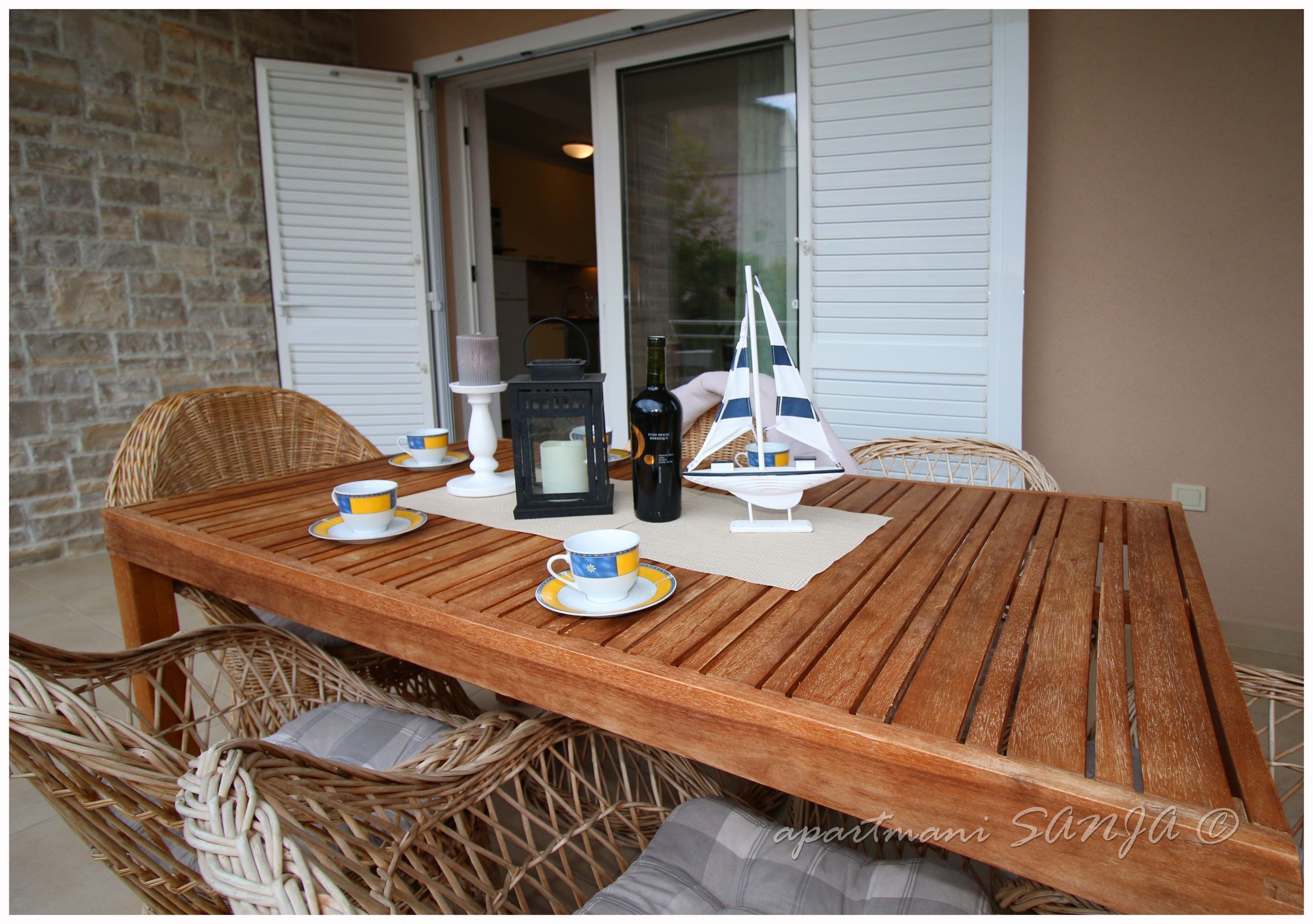 A wooden table with chairs, a ship model, and a bottle.