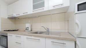 Eine moderne Küche mit weißen Schränken, einer Edelstahl-Spüle und einem eingebauten Backofen.