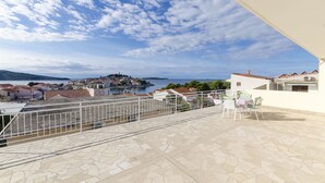 Eine Terrasse mit Blick auf eine Küstenstadt, einem Geländer und einem Tisch mit Stühlen.