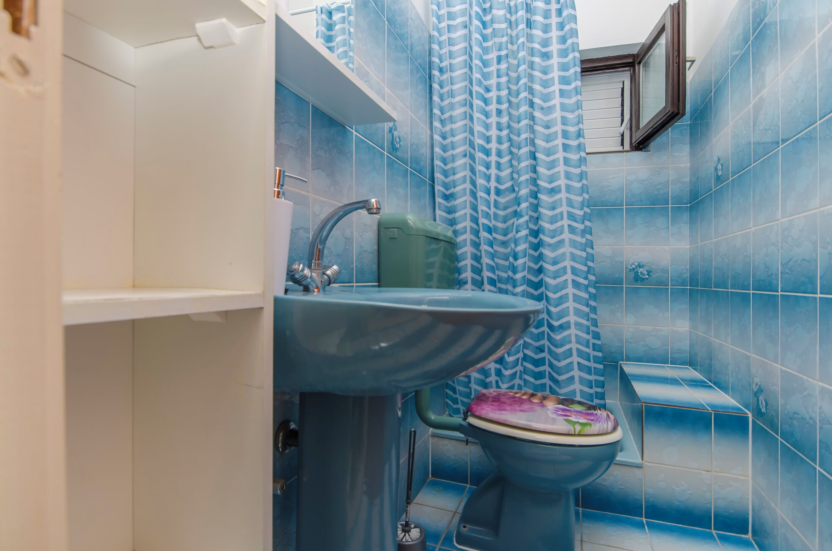 A bathroom with blue tiles, a sink, a toilet, and a shower curtain.