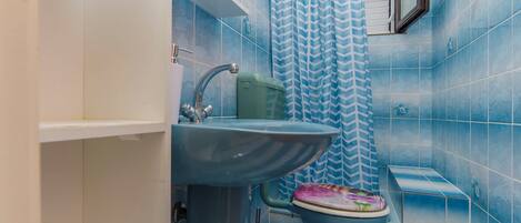 A bathroom with blue tiles, a sink, a toilet, and a shower curtain.