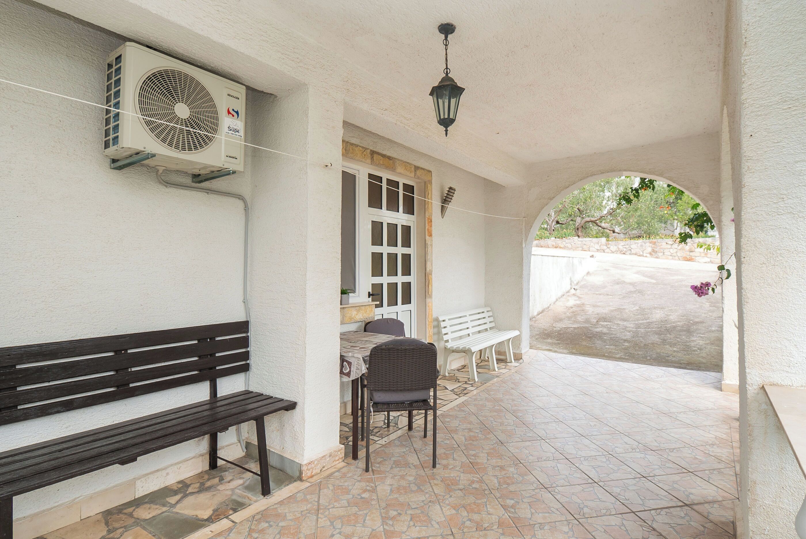 A covered outdoor area with a bench, a table, and chairs.