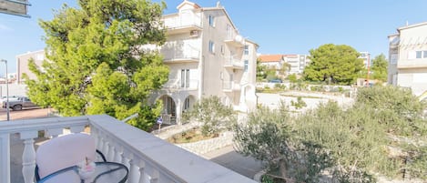 A balcony with a table and chairs, overlooking a residential area with buildings and trees.