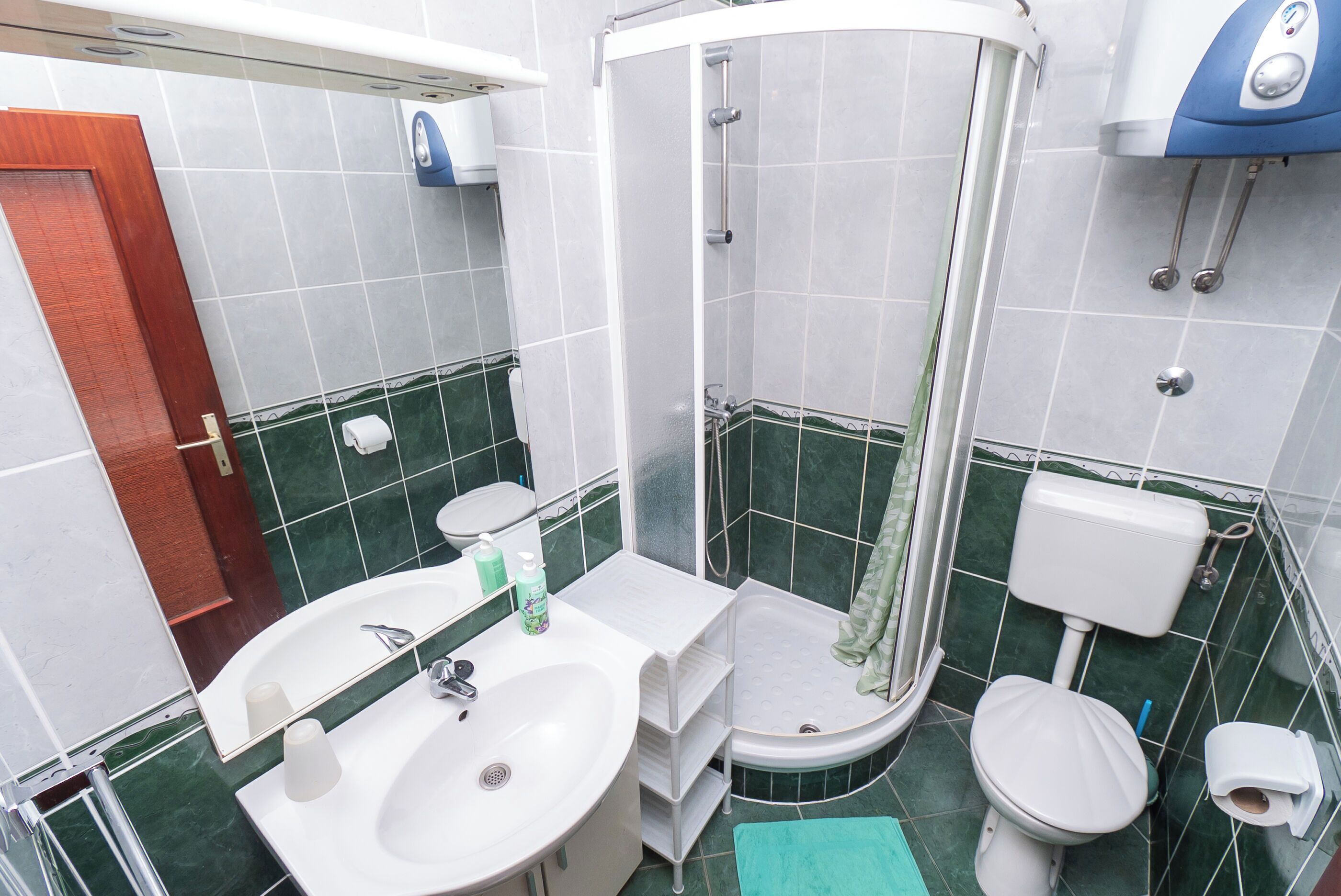 A bathroom with a sink, mirror, toilet, and shower.