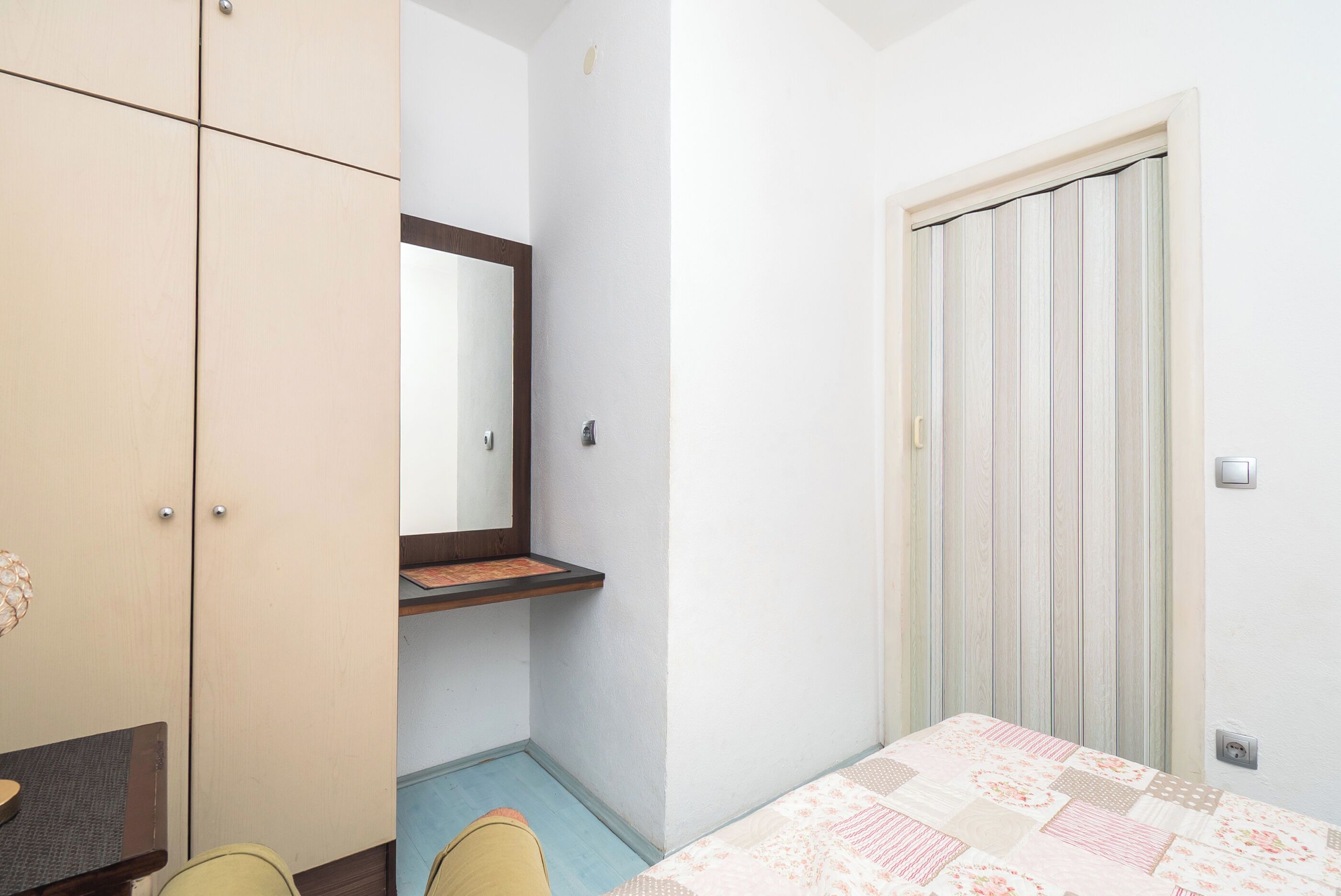 A bedroom with a bed, a wardrobe, a mirror, and a door.