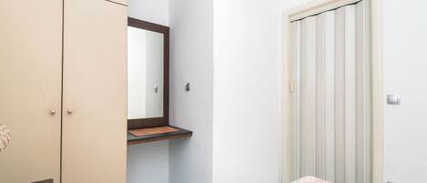 A bedroom with a bed, a wardrobe, a mirror, and a door.