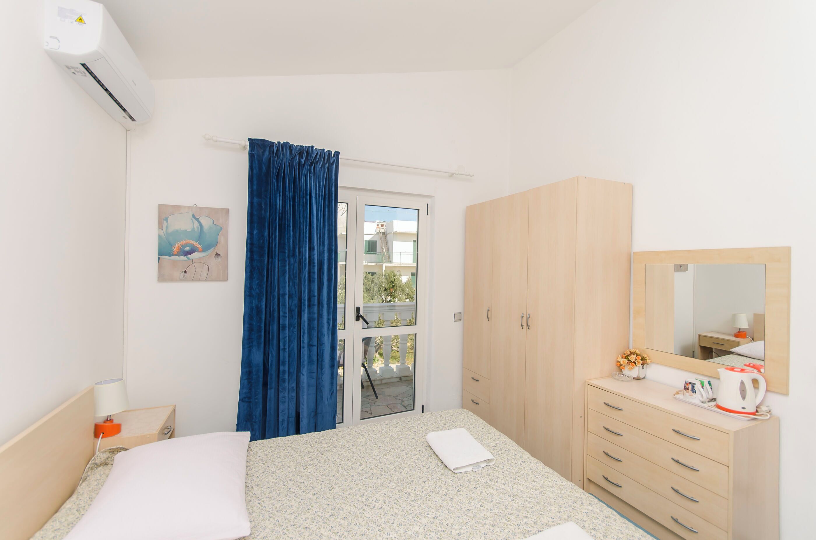 Un dormitorio con una cama, un tocador, un espejo y una ventana con cortinas.