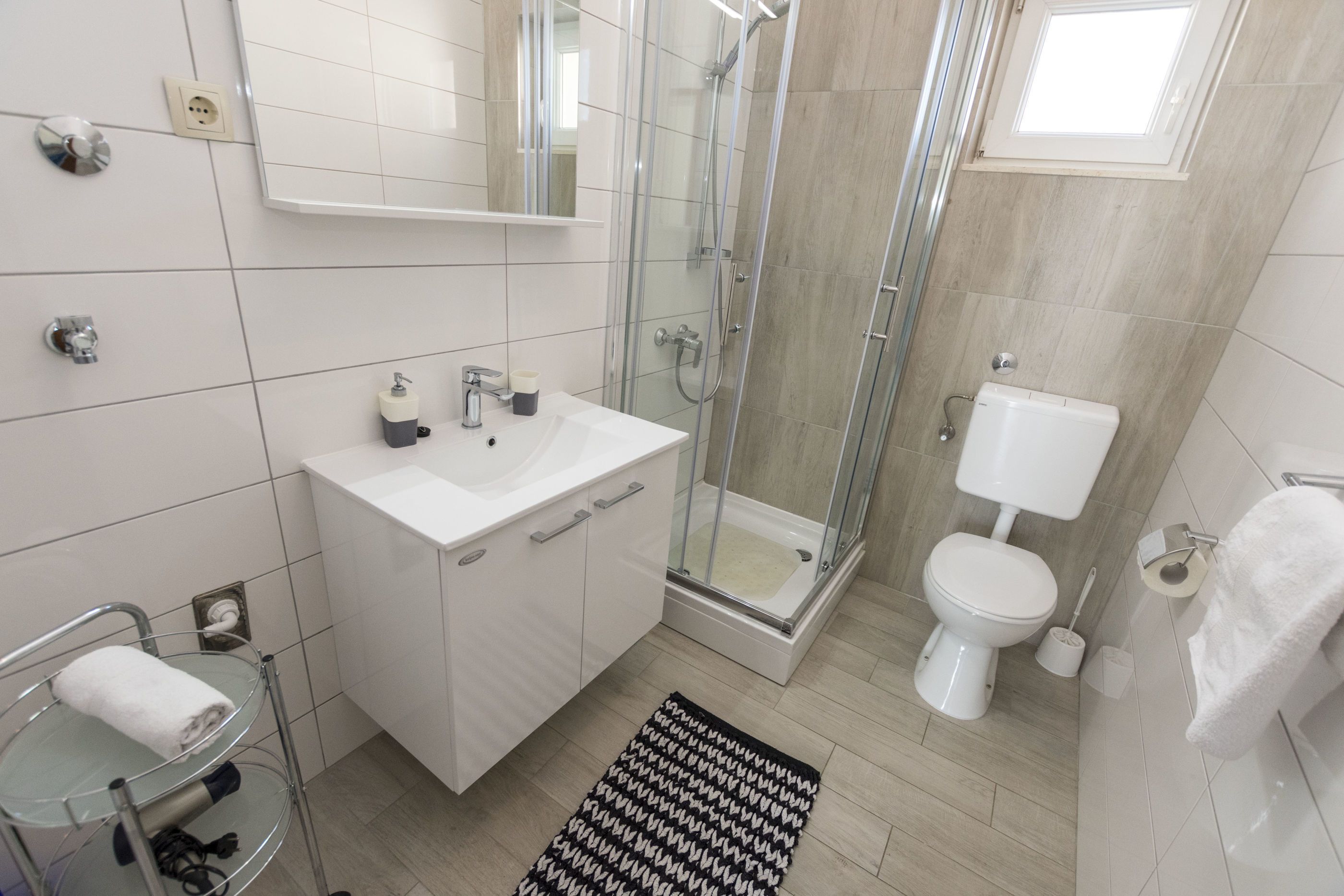 A modern bathroom with a glass-enclosed shower, a white sink, and a toilet.