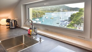 Een keuken met een groot raam met uitzicht op een jachthaven met boten.