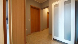 Un couloir avec une porte en bois, une porte blanche et un meuble blanc.