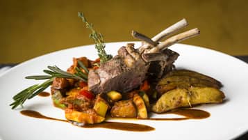 Une assiette de nourriture comprenant un jarret d’agneau, des légumes et des pommes de terre.