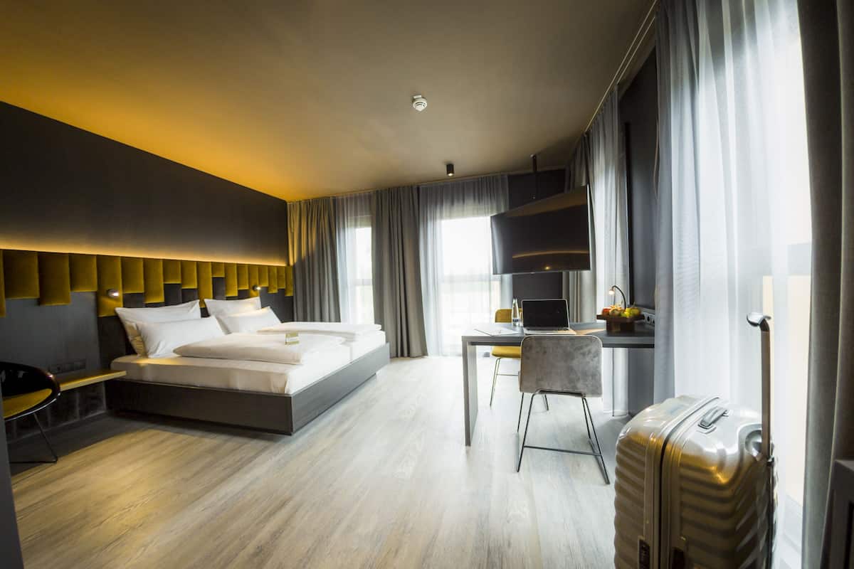 Ein modernes Hotelzimmer mit einem großen Bett, einem Schreibtisch und einem Koffer.