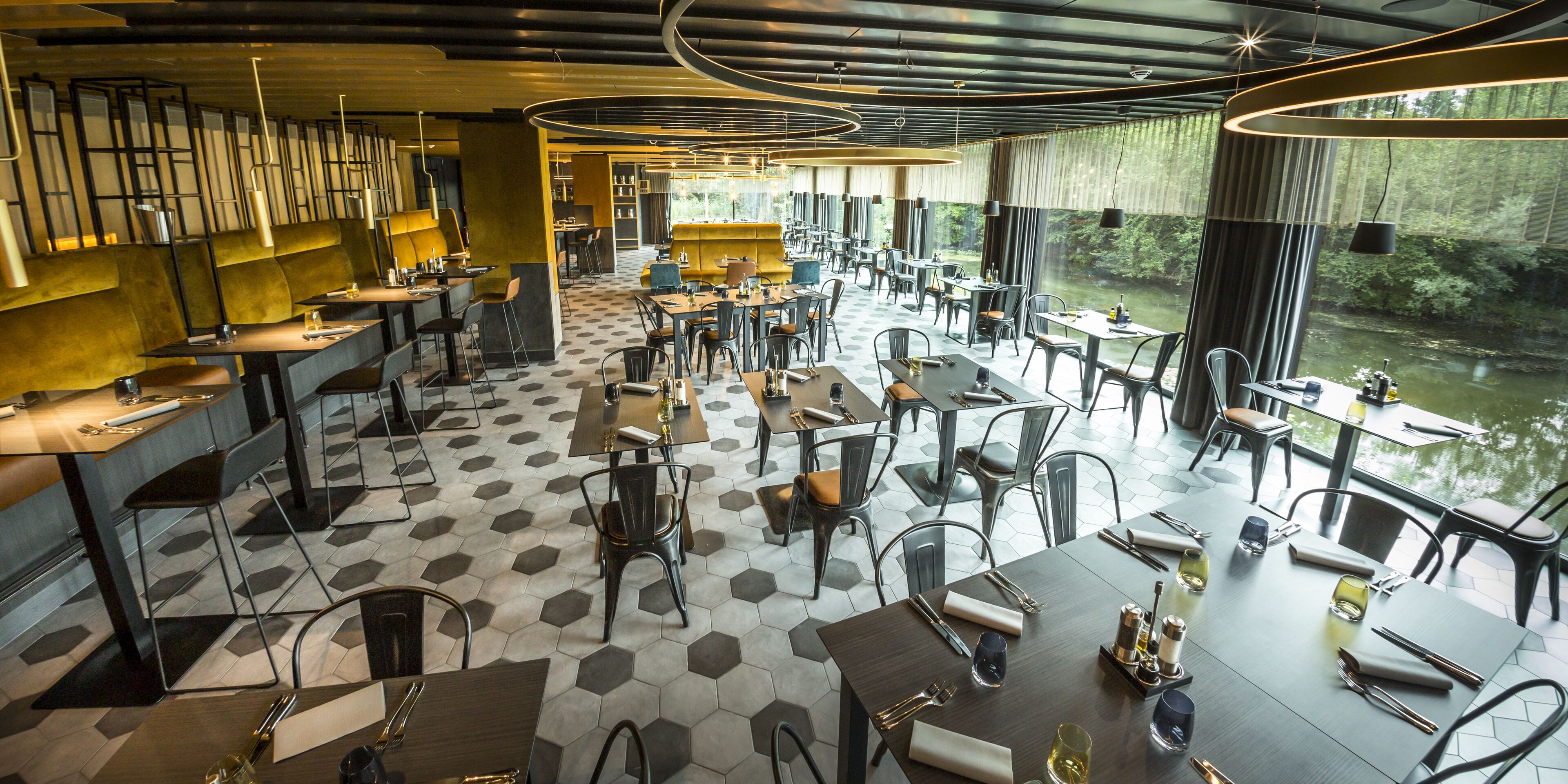 Ein Restaurant mit sechseckischem Fliesendesign, modernen Möbeln und großen Fenstern mit Flussblick.