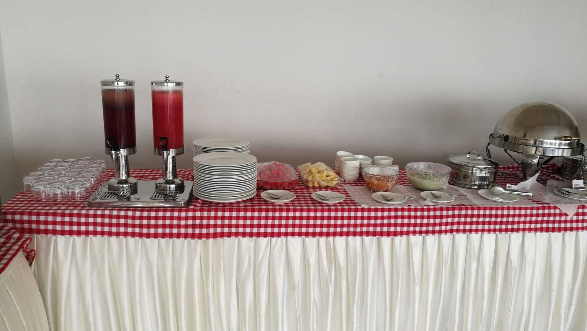 A buffet setup with various food items and serving utensils on a checkered tablecloth.