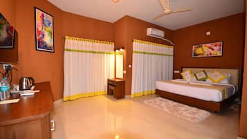 A hotel room with a bed, a desk, a chair, a coffee maker, and a ceiling fan.