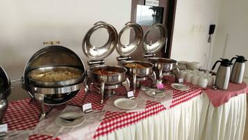A buffet setup with multiple stainless steel serving dishes and a red and white checkered tablecloth.