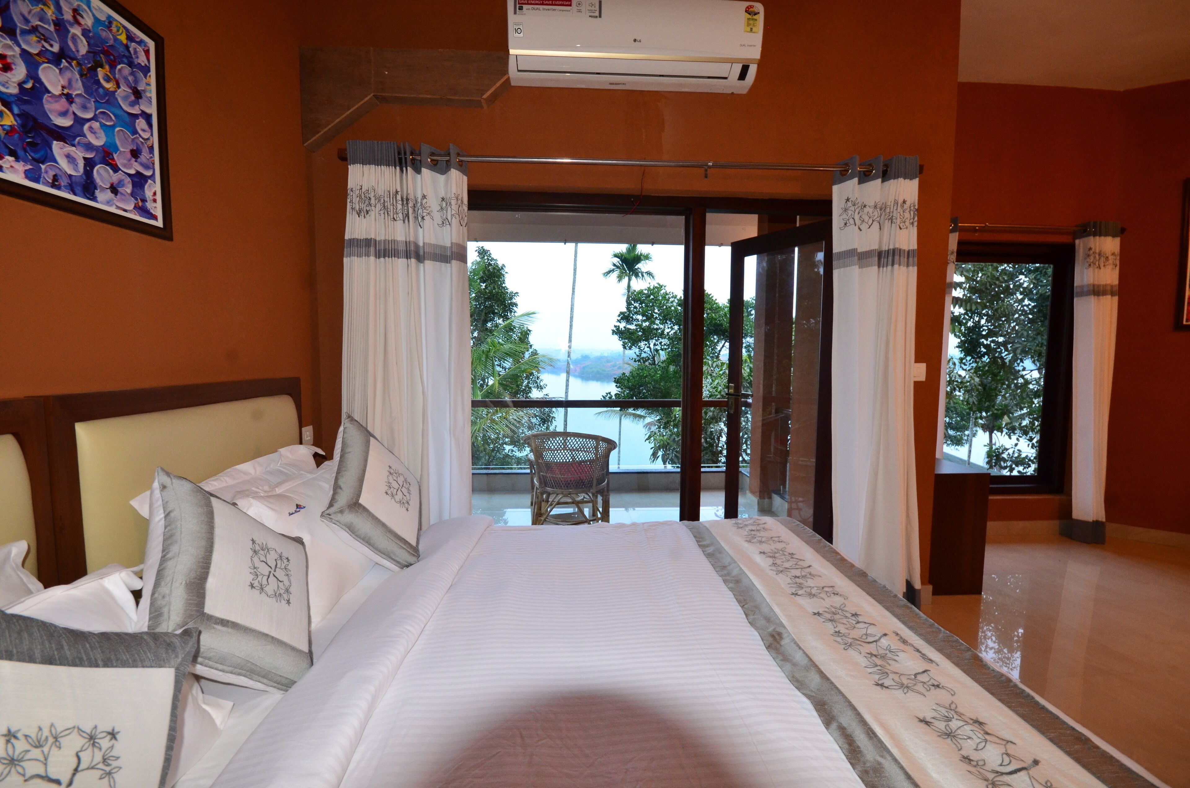 A hotel room with a large bed, a balcony with a view of the mountains, and a chair.