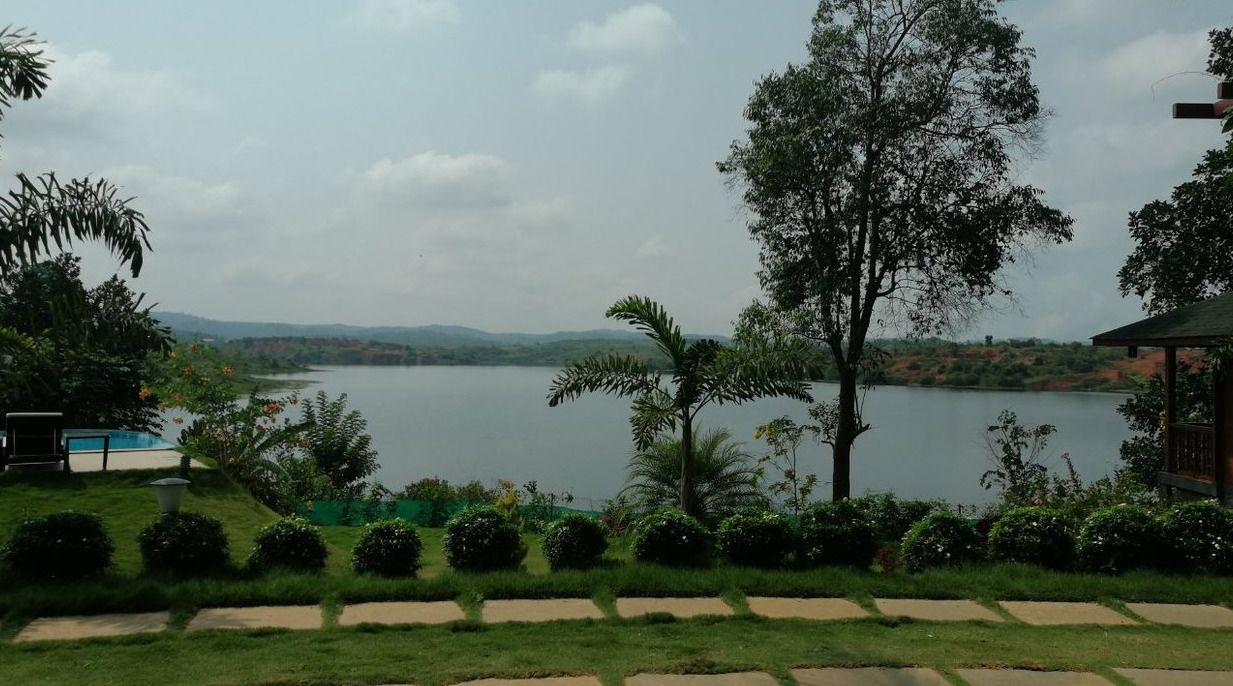 A lakeside view with a gazebo, a swimming pool, and a well-maintained garden.