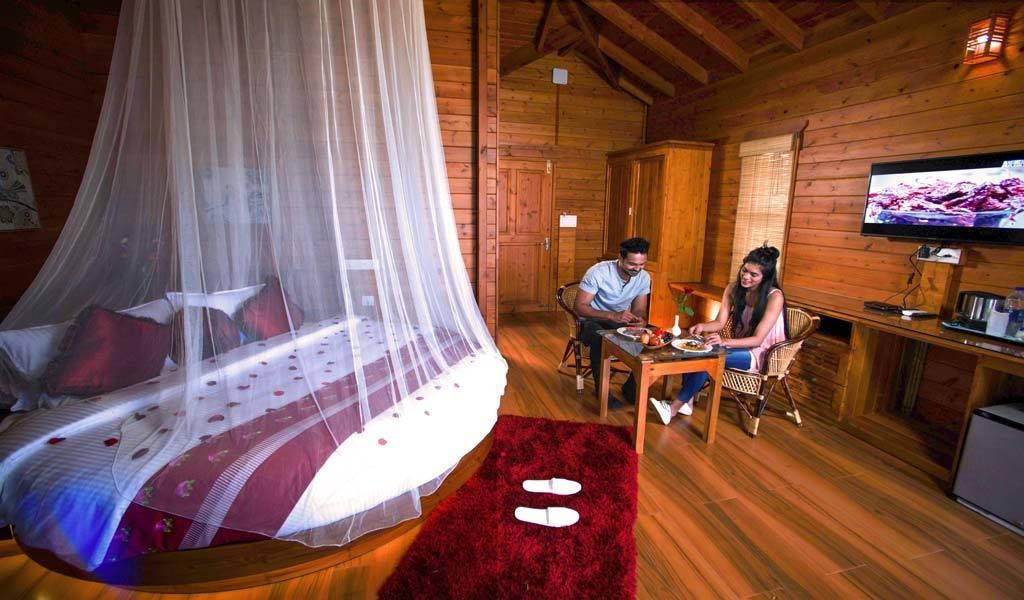Eine Holzhütte mit einem Himmelbett, einem Fernseher und einem Essbereich.