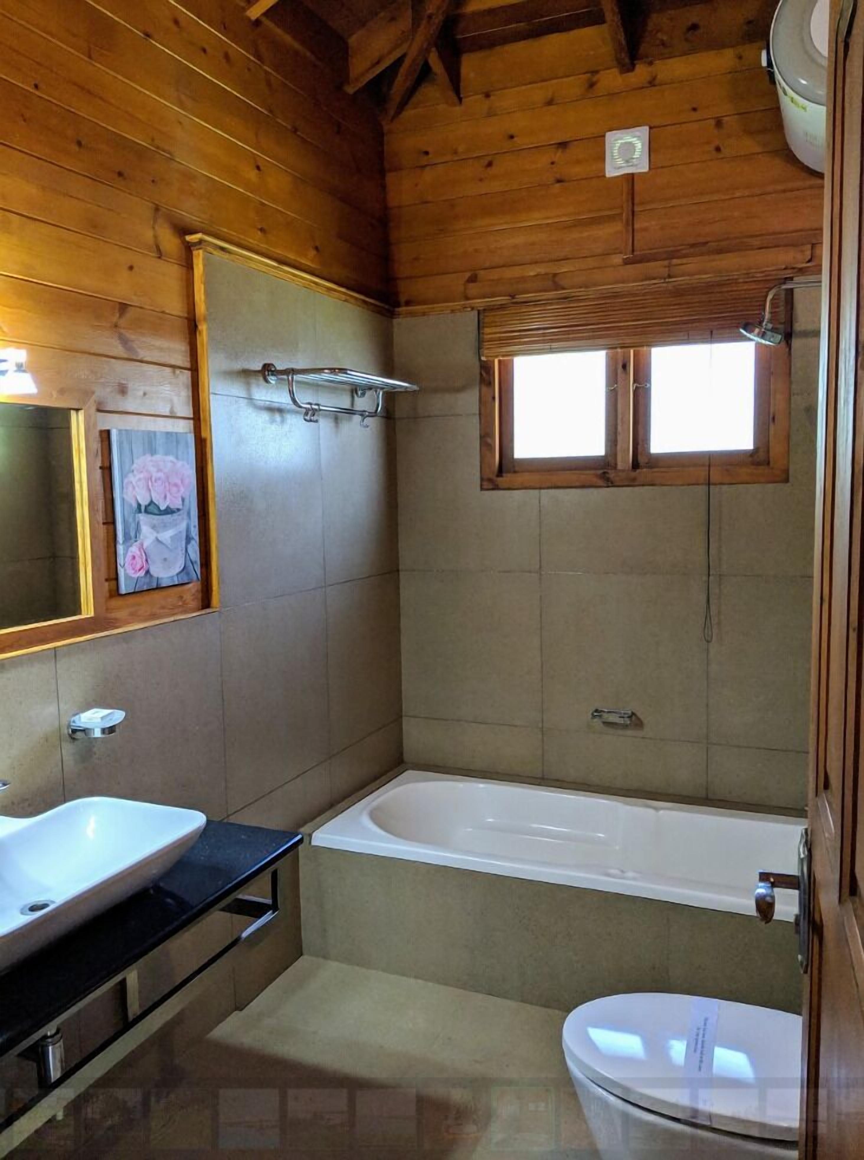 A bathroom with a wooden interior, a white bathtub, a sink, and a toilet.