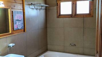 A bathroom with a wooden interior, a white bathtub, a sink, and a toilet.