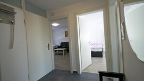 A hallway leading to a bedroom with a bed, a nightstand, and a small table. - Ferienwohnung  Bergisch Gladbach GL5 (Bergisch Gladbach)