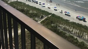 Een strand met mensen, parasols en uitzicht op de oceaan.