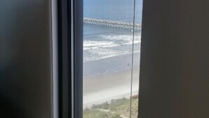 Een kamer met een groot raam met uitzicht op een strand en een pier.