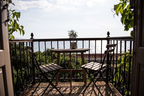 A balcony with a table and two chairs, overlooking a body of water. - Olive Press Hotel & Apartments (Lesvos)
