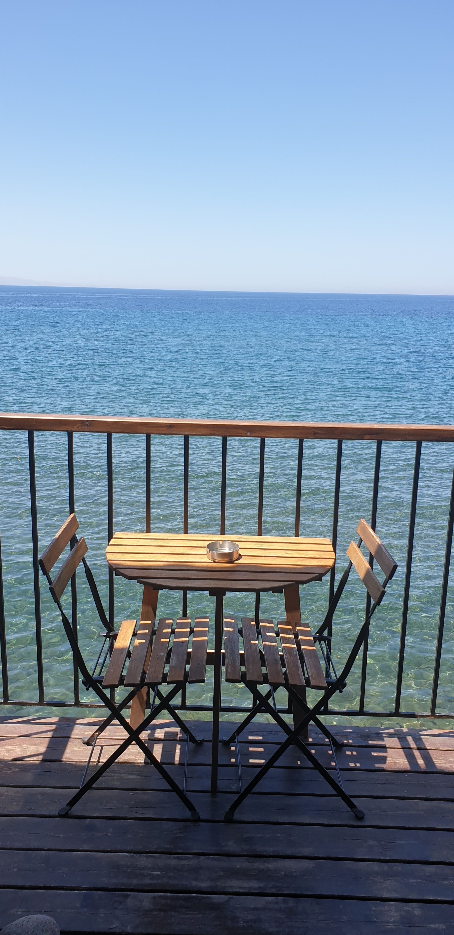 A wooden deck with a table and chairs overlooking a body of water.