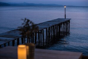 Une jetée en bois s’avançant dans une étendue d’eau calme, avec un seul lampadaire à son extrémité.