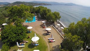 Ein Strandhotel mit Schwimmbad, Liegestühlen und Sonnenschirmen.