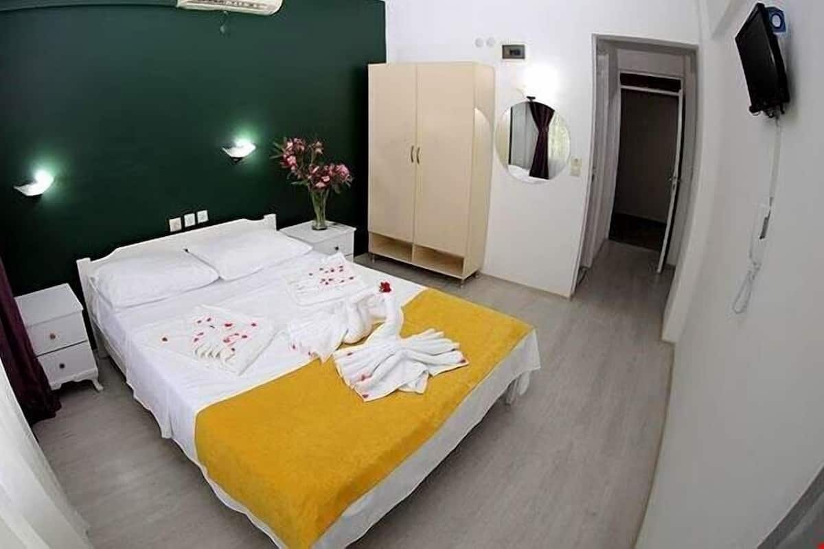 A hotel room with a bed, a wardrobe, a mirror, and a nightstand.