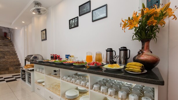 A well-lit kitchen with a buffet setup, including various food items, a coffee station, and a vase with flowers. - Hanoi Cozy House (Hanoi)
