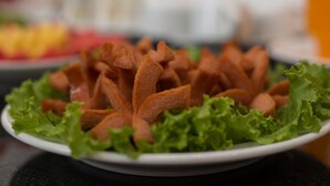 A plate of food with triangular-shaped items on a bed of green lettuce leaves. - Hanoi Cozy House (Hanoi)