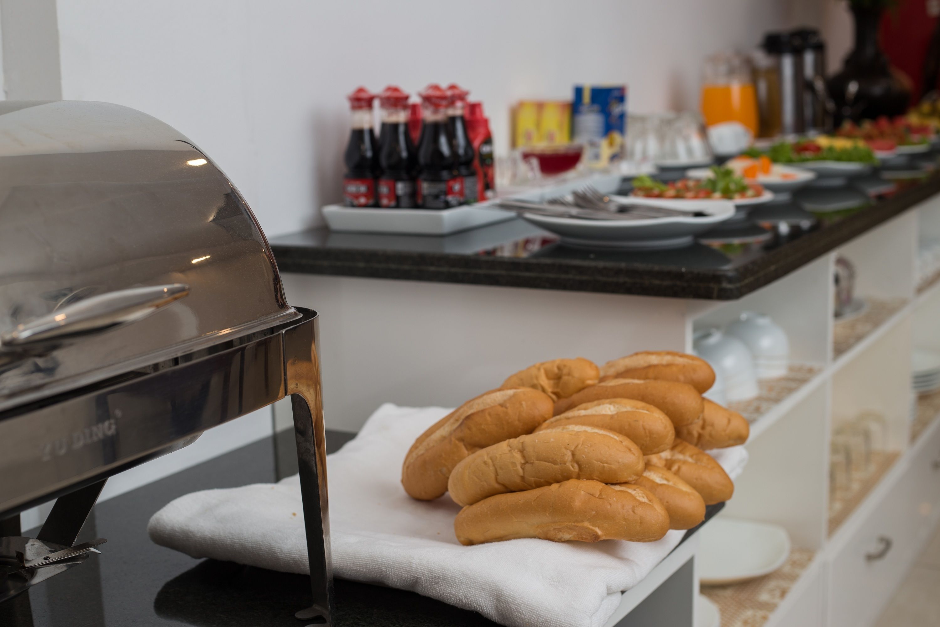 A buffet setup with a grill, bread, and various condiments.