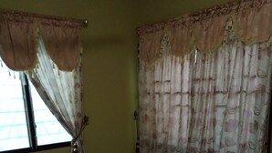 A room with a bed, curtains, and a window.