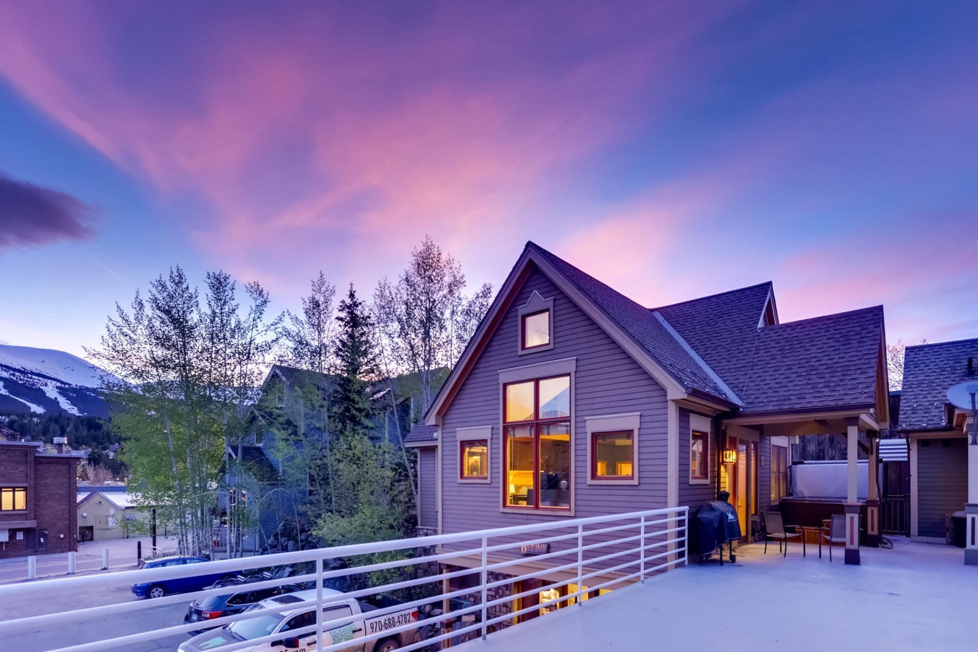 A modern two-story house with a covered patio and a view of a mountain range.