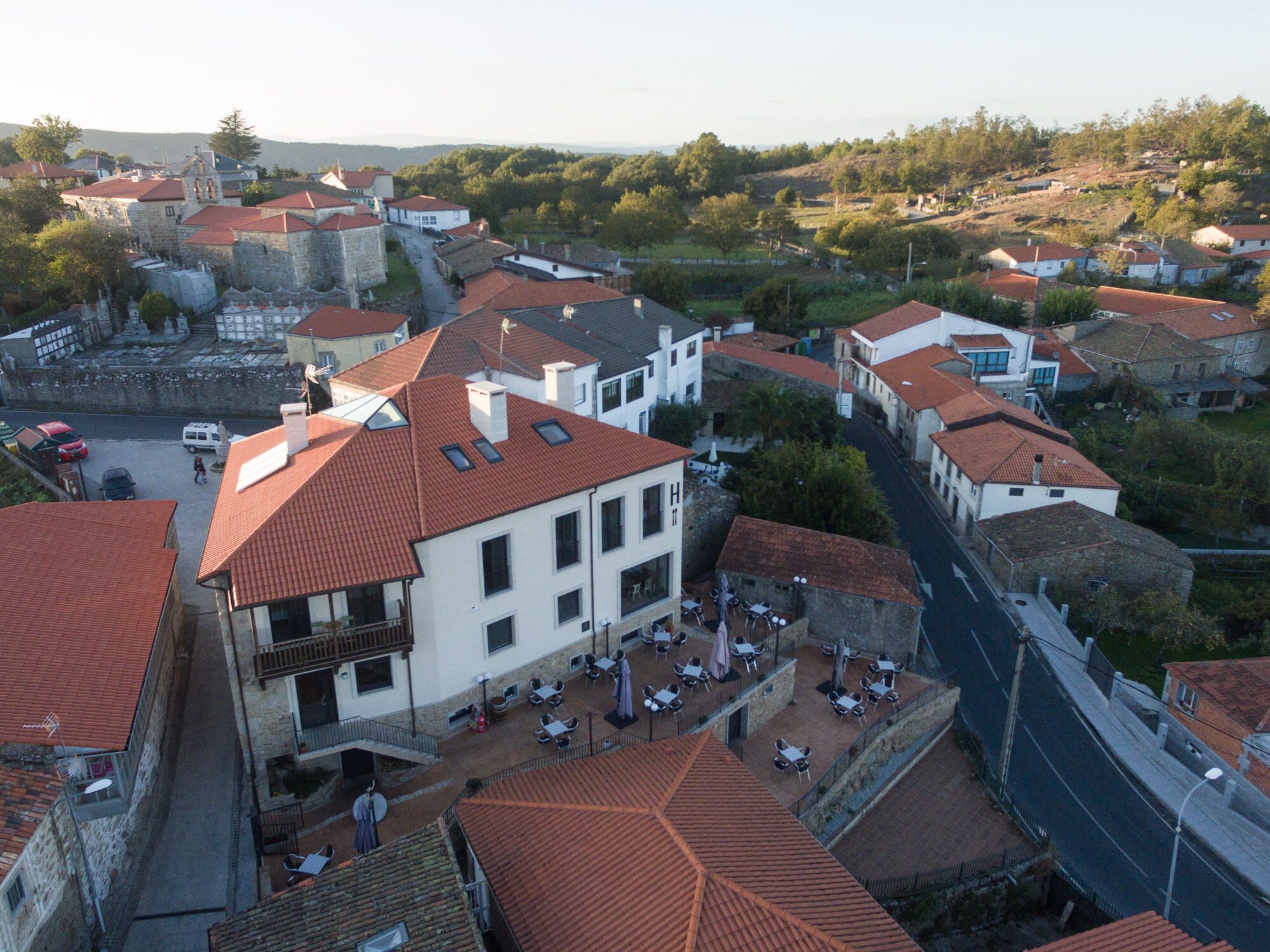 Un edificio blanco con techo rojo, varias ventanas y terraza.
