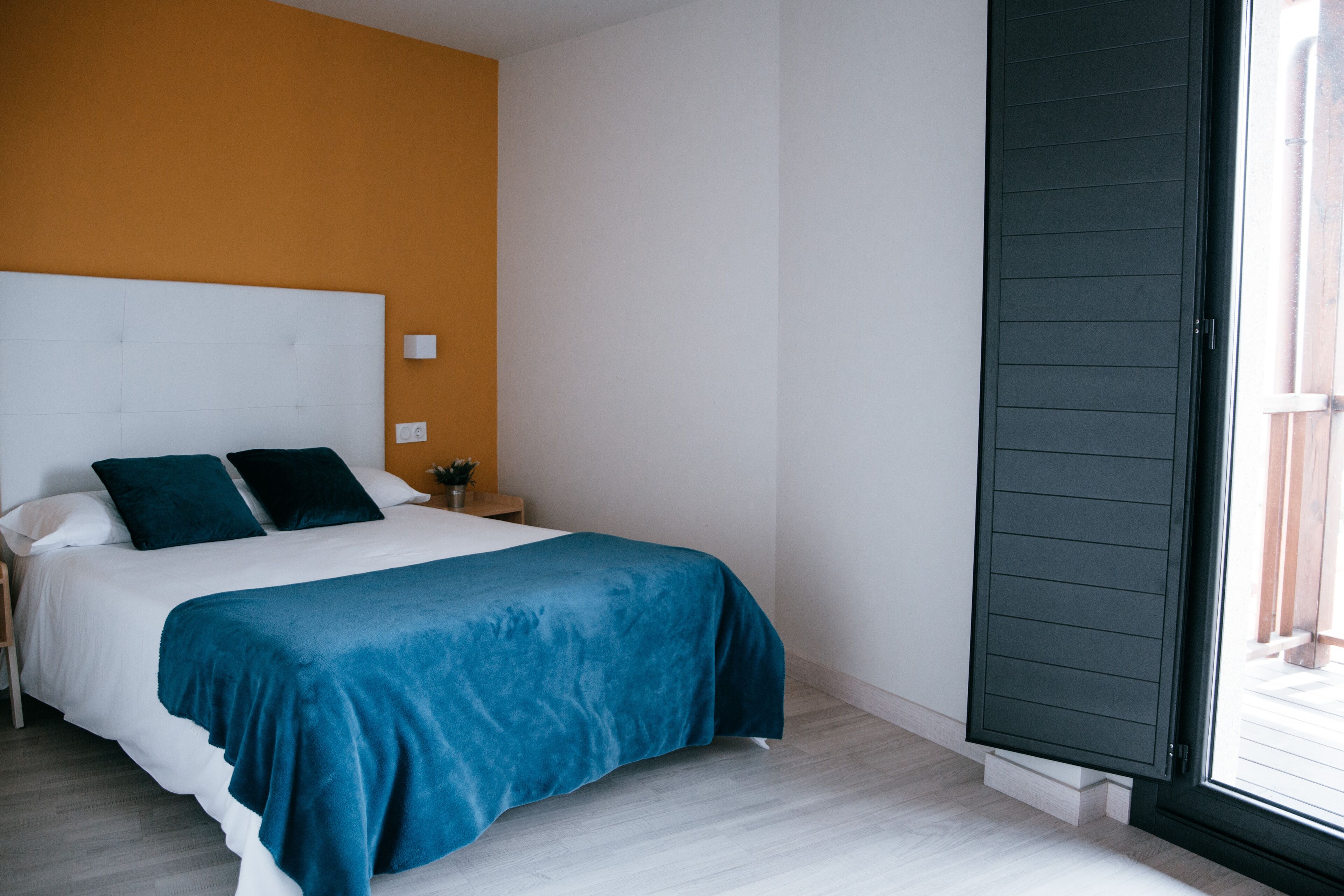 A bedroom with a bed, a nightstand, a window, and a door.