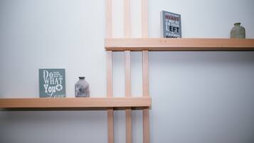 Two wooden shelves against a plain wall, each holding a book and a jar.