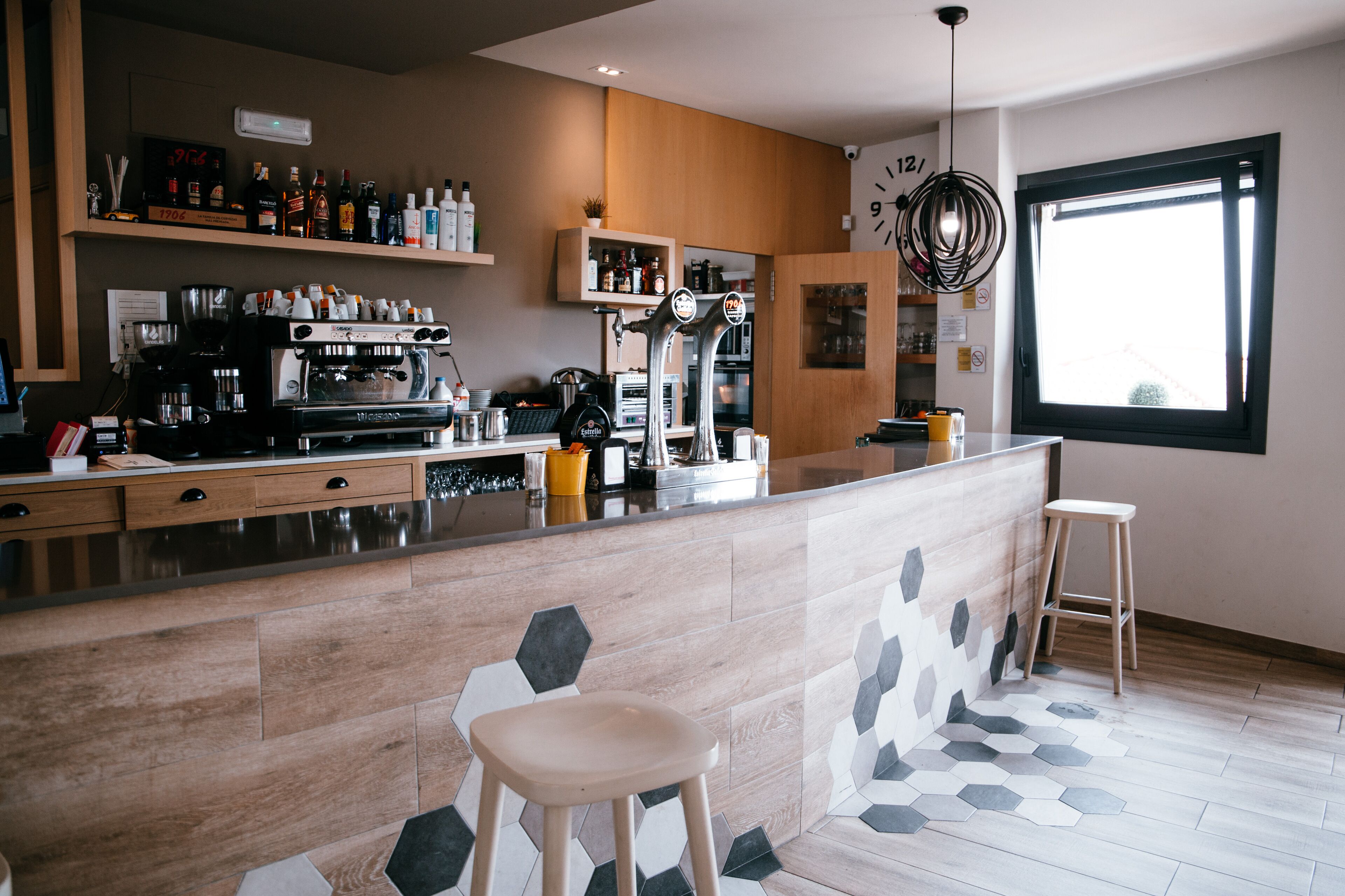 Een moderne keuken met een centraal eiland, barkrukken en een groot raam.
