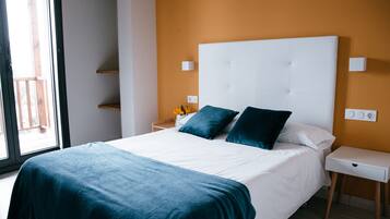 Un dormitorio con una cama grande, cabecera blanca y una mesita de noche con lámpara.