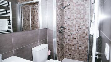 Un baño moderno con ducha de vidrio, inodoro blanco y lavamanos.