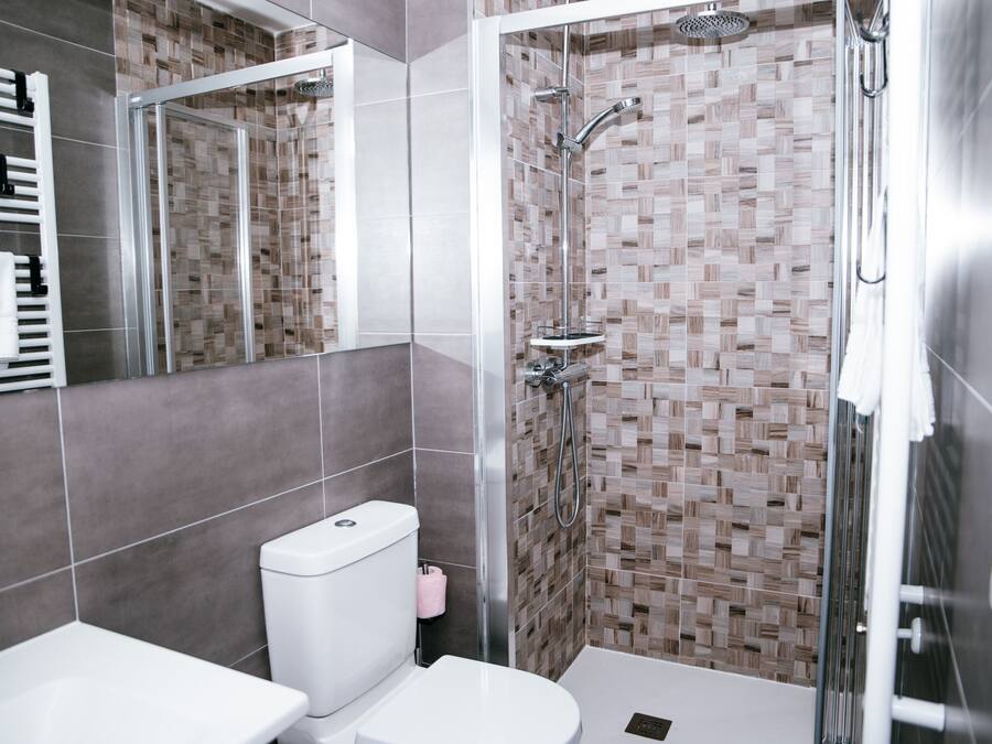 Un baño moderno con ducha de vidrio, inodoro blanco y lavamanos.