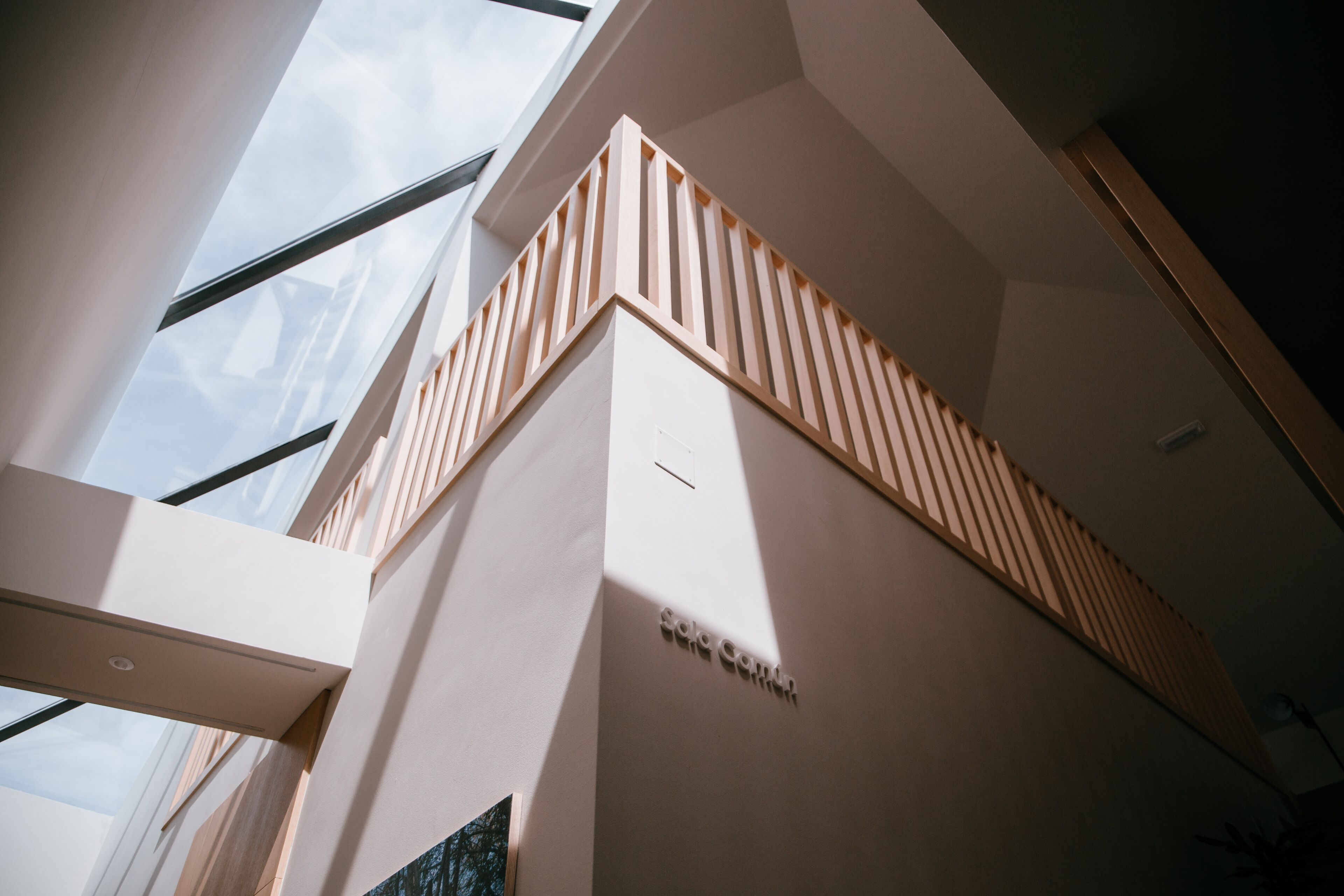 Ein modernes Interieur mit hohen Decken, Dachfenstern und einer Holzgeländer.