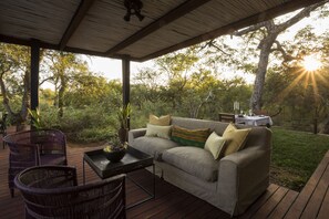 Een terras buiten met een bank, stoelen en een tafel.