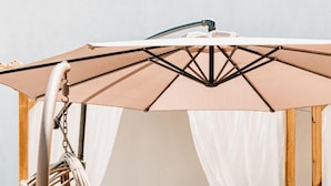 A hanging chair, a sofa, and a table under a canopy. - La Smeralda - Boutique Rooms and Breakfast (Golfo Aranci)