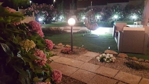 A garden area with a paved walkway, a spherical light fixture, and a seating area with a chair and table. - La Smeralda - Boutique Rooms and Breakfast (Golfo Aranci)